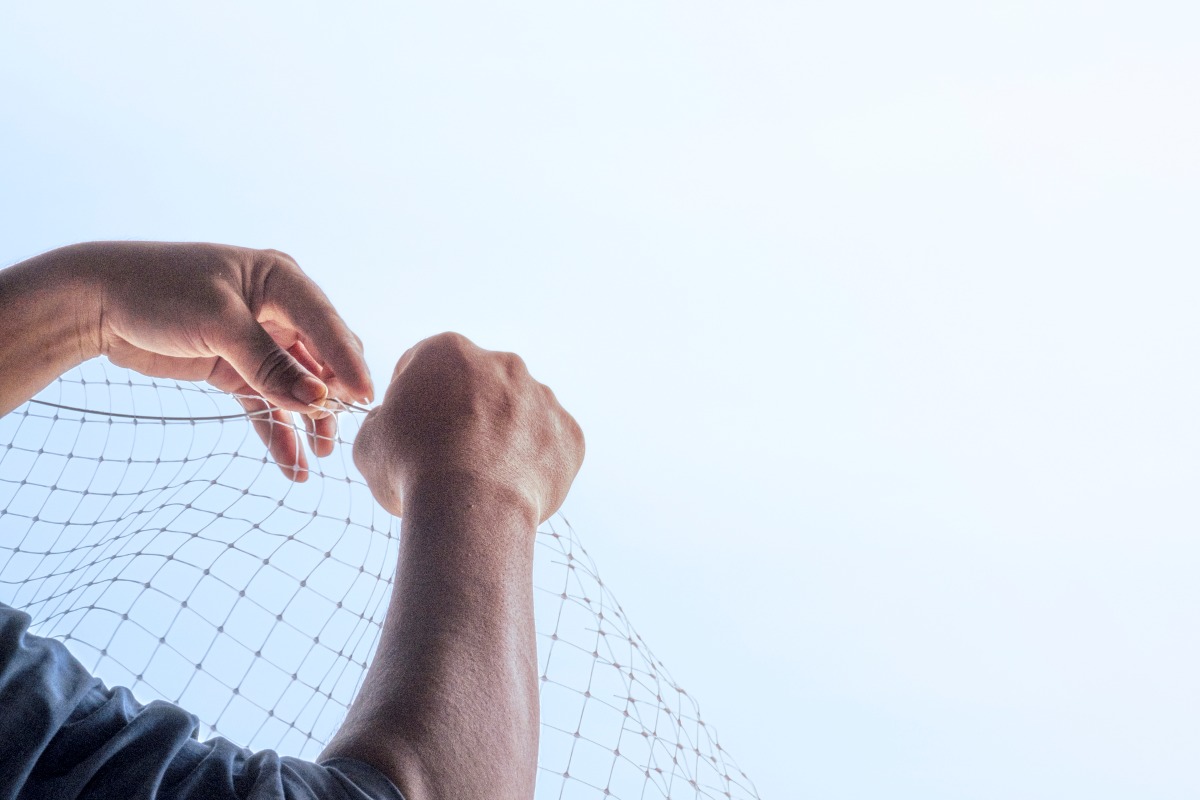 pair of hands working on a bird net