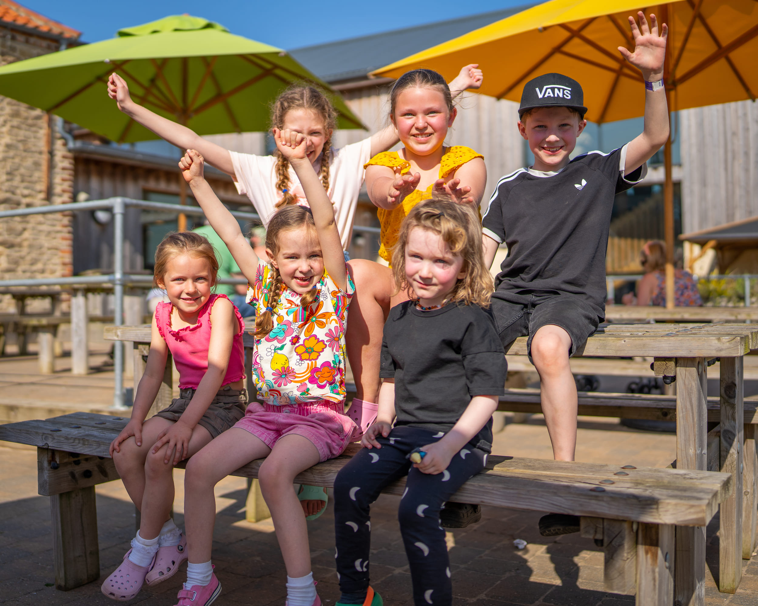 A group of smiling children sitting at a picnic bench at William's Den