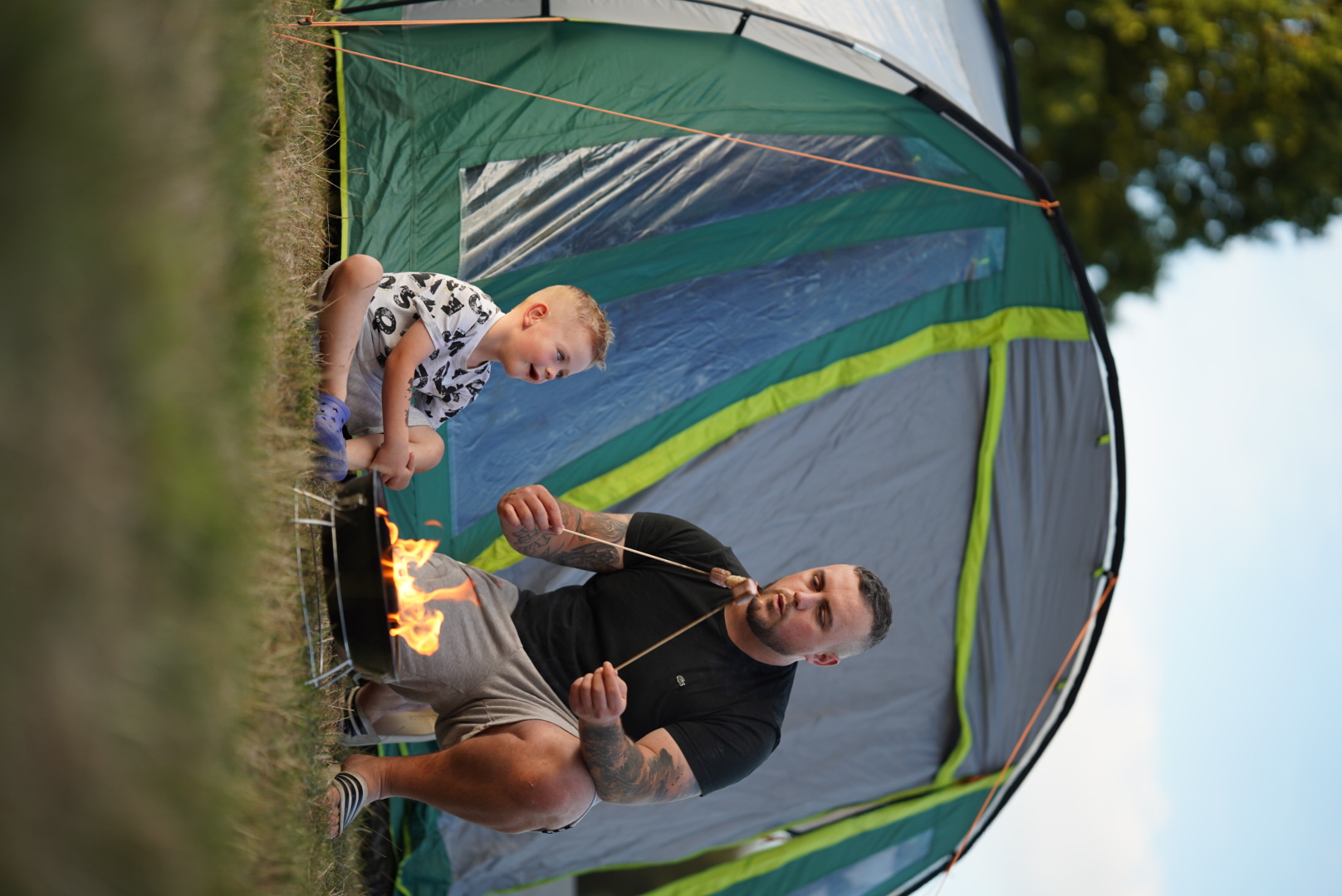 A young boy and his dad enjoy marshmallows outside a tent at William's Den