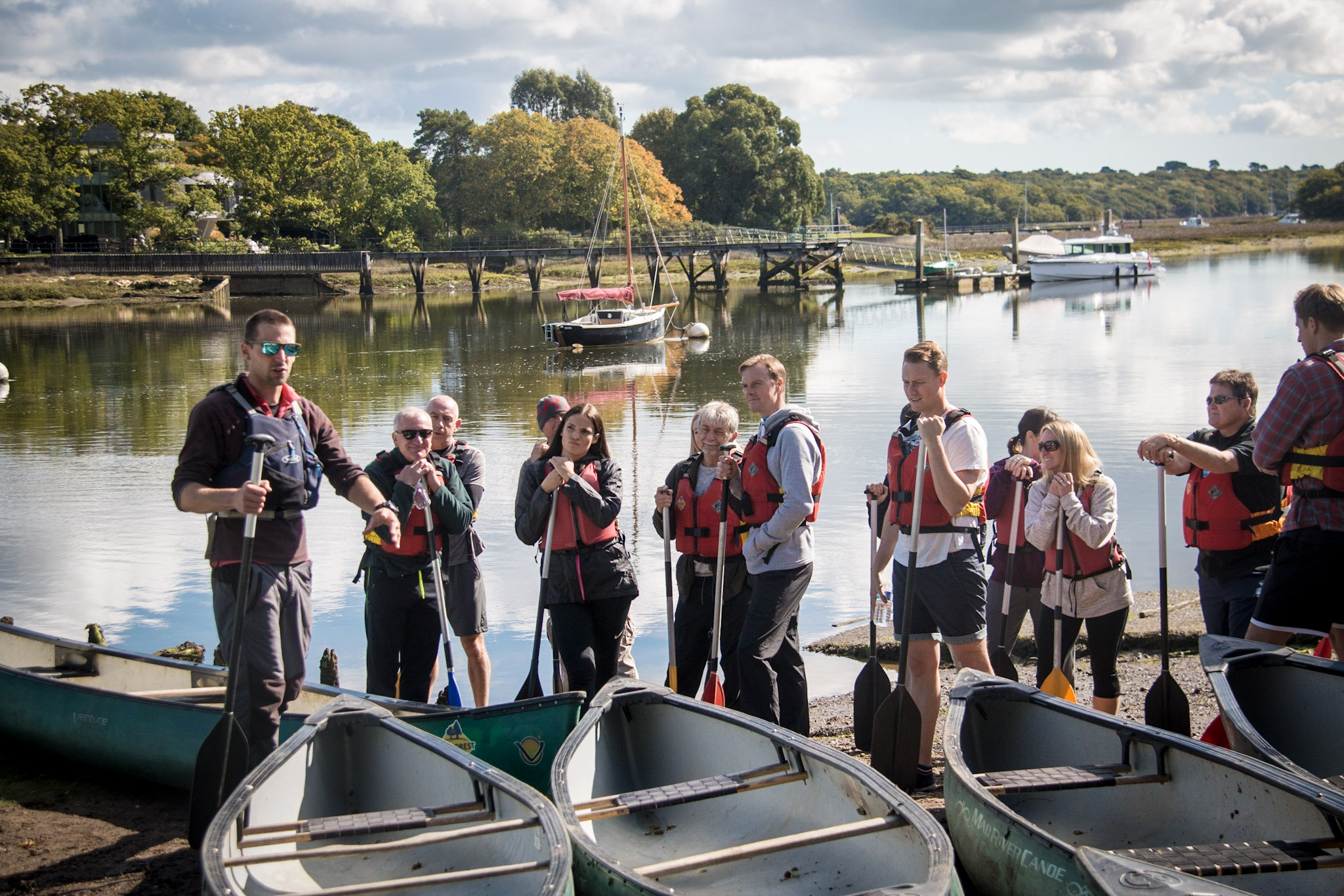 An adult social group in front of several canoes.