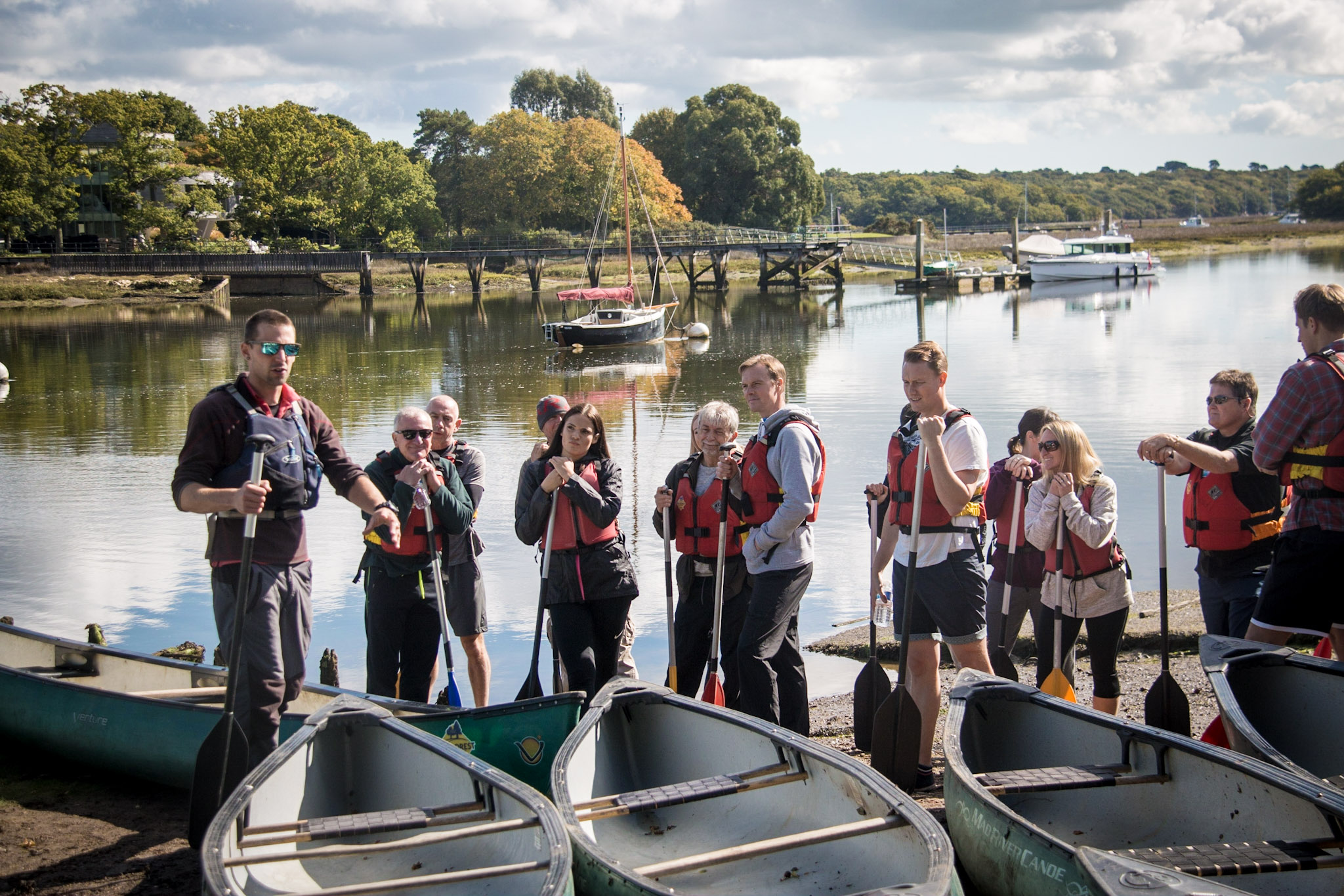 An adult social group in front of several canoes. 