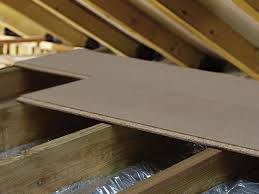 Attic flooring installation with chipboard panels over wooden joists.