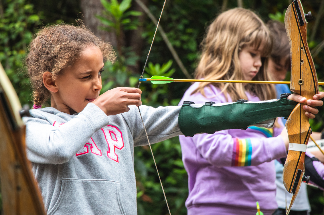 A girl taking part in archery during school residential