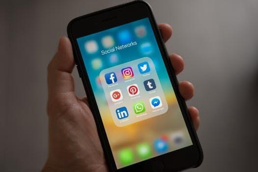 Hand holding a cell phone, with social media icons on the screen Hand holding a cell phone, with social media icons on the screen